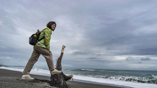 Full length of woman standing on beach against sky