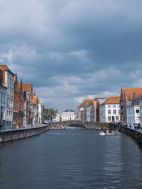 Buildings by river against sky