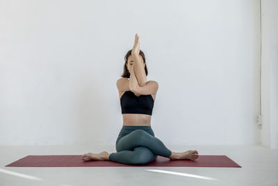 Full length of young woman doing yoga at home