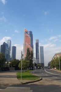 City street by modern buildings against sky
