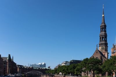 Buildings in city against clear blue sky