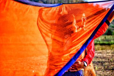 Man embracing woman seen through orange dupatta