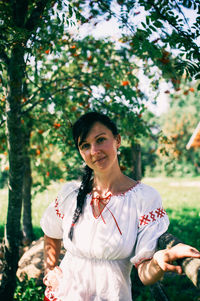 Young woman standing in front of tree