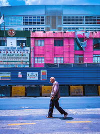 Full length side view of man walking on street in city