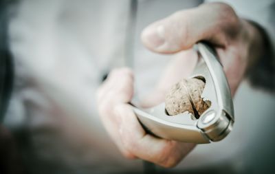 Close-up of hand breaking walnut using nutcracker