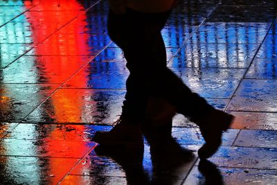 Low section of man standing on wet street