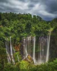 Scenic view of waterfall in forest against sky