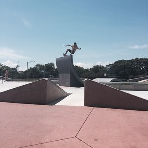 Young man performing stunt at skateboard park