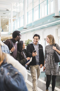 Cheerful male and female students walking in university