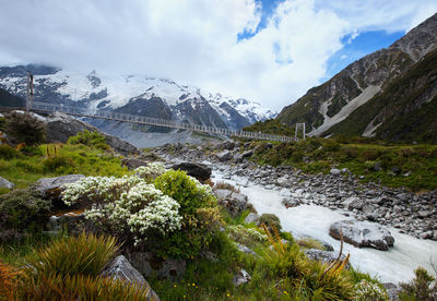 Scenic view of stream by snowcapped mountains against sky