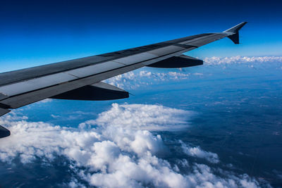 Cropped image of airplane wing over clouds