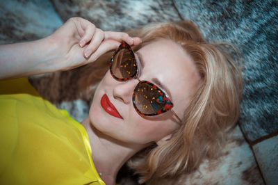 High angle view of woman wearing sunglasses lying on bed at home