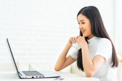 Young woman using mobile phone on table