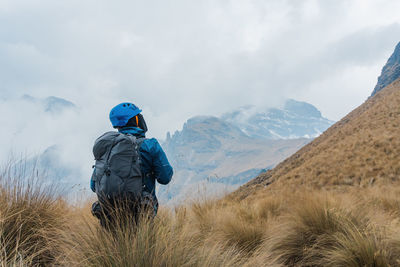 Rear view of man standing on mountain against sky