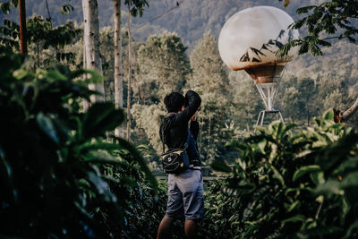 Rear view of woman standing against plants