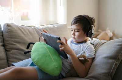 Boy using mobile phone while sitting on sofa at home