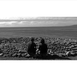 Rear view of couple sitting on beach