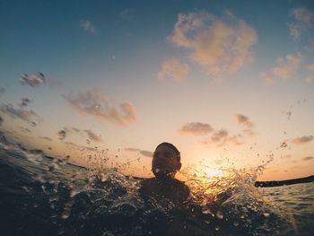 Close-up of boy swimming in sea during sunset
