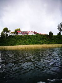 House by lake against sky