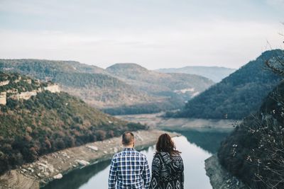 Rear view of people looking at mountains against sky