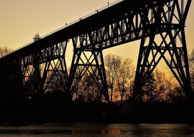 Low angle view of bridge over river during sunset