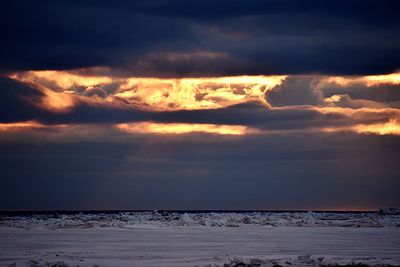Scenic view of frozen sea against cloudy sky during sunset