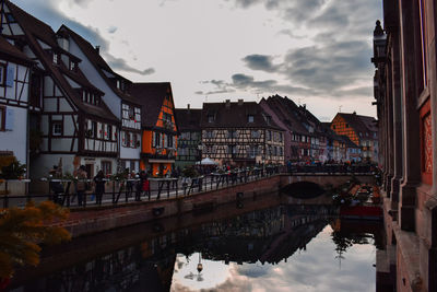 Reflection of buildings in canal against sky in city