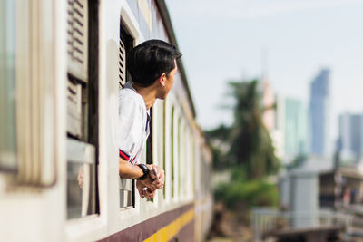 Side view of young man looking through train window