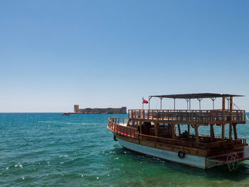 Ferryboat with turkish flag against maiden's castle or kizkalesi. kizkalesi, mersin province, turkey
