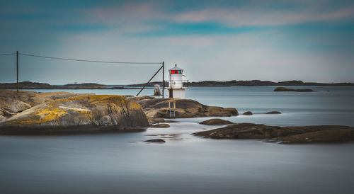 Lighthouse by sea against sky