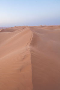 Sand dunes in desert against clear sky