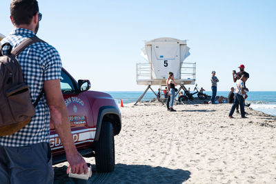 People standing on beach against clear sky