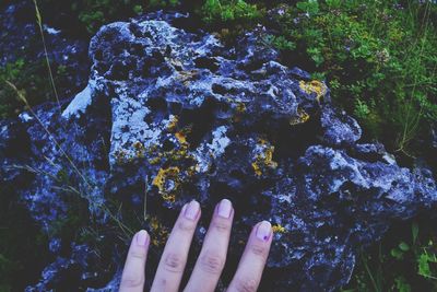 Cropped hand touching rock