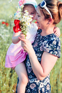 Low angle view of woman carrying daughter holding flower bouquet