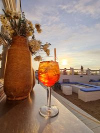 Wine glass on table against sky during sunset