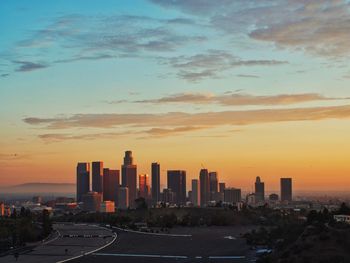Modern buildings in city against sky during sunset