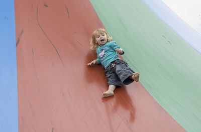 Blond barefoot toddler sliding