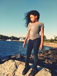 Full length of girl standing on shore against clear sky