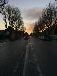 Road amidst trees against sky during sunset