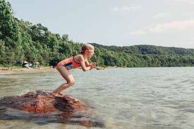 Full length of girl jumping at beach against sky