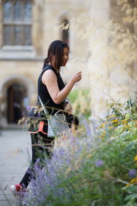 Side view of young woman standing by plants