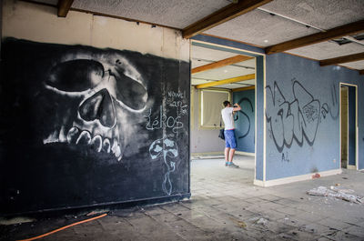 Man standing by graffiti on wall