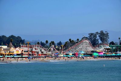 Amusement park at beach against clear blue sky