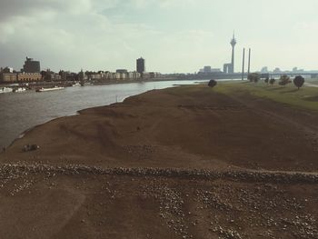 Scenic view of river in front of city against sky