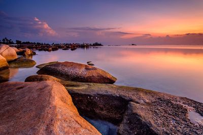 Rocks in sea at sunset