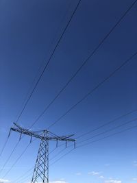 Low angle view of power lines against clear blue sky