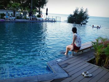 Woman dangling legs in swimming pool