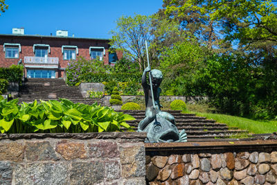 Statue by building against sky