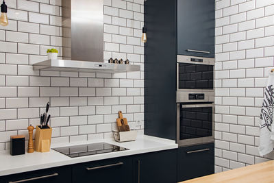 Modern stylish trendy kitchen with white tile and dark facades, real photo