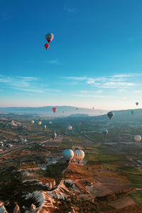 Hot air balloons flying over landscape against sky